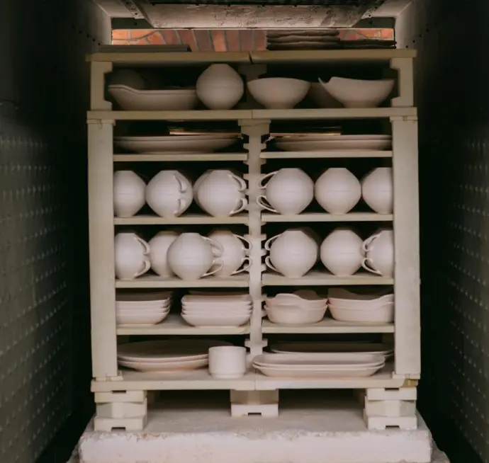 A front-loading kiln, doors open, loaded with pottery for a bisque firing